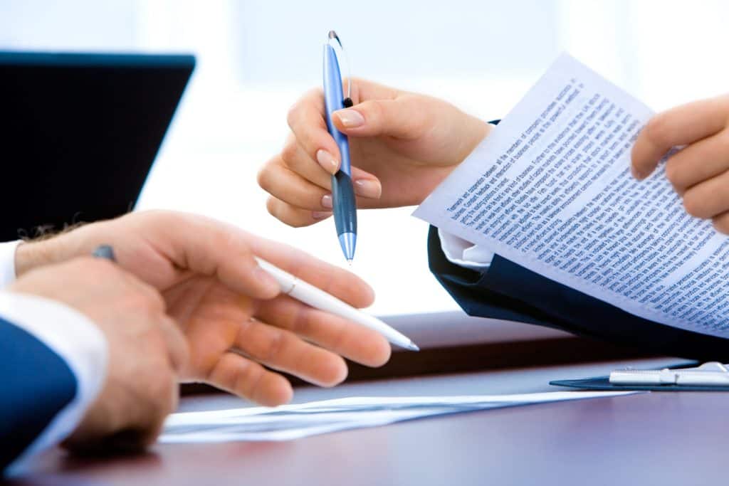 Deux mains tenant des stylo et un papier dans un bureau
