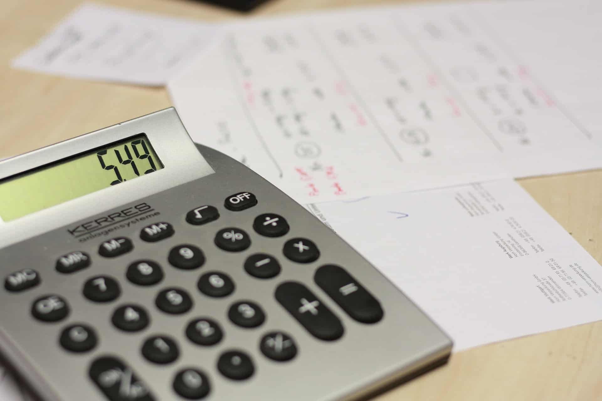 Une calculatrice et des factures impayées en arrière plan